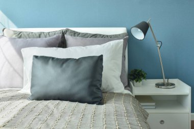 Yatakta modern tarzı masa lambası ile gri, koyu gri ve beyaz renkli yastıklar