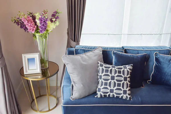 Sofá clásico moderno azul marino y almohadas retro, grises y azules con un precioso jarrón de orquídea en la mesa auxiliar en la esquina de estar — Foto de Stock
