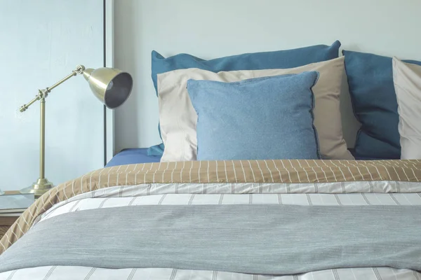 Синьо-бежеві подушки на ліжку та хромова лампа для читання — стокове фото