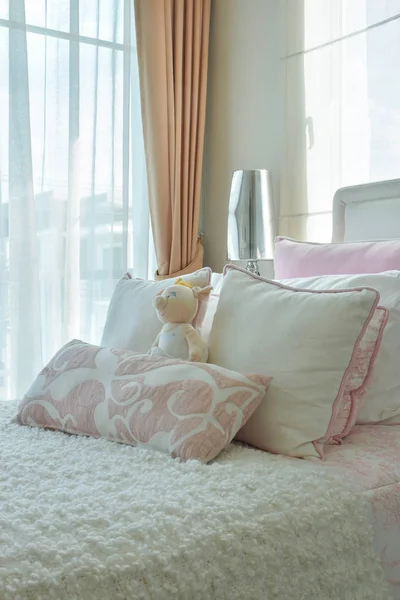 Růžové a béžové polštáře na postel vedle okna — Stock fotografie