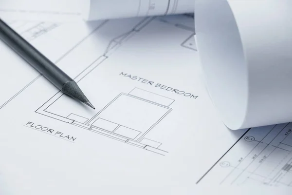 Lápis preto sobre papel de desenho arquitetônico e rolos para construção — Fotografia de Stock