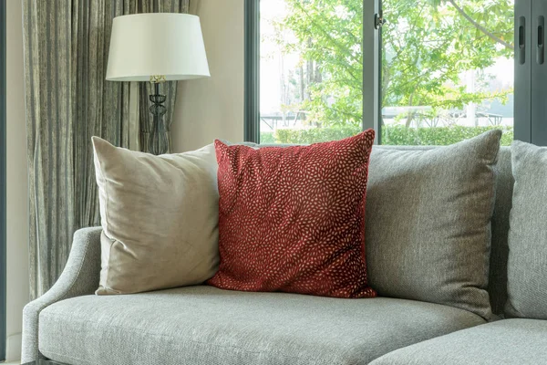 Moderna sala de estar con almohadas rojas en sofá gris y lámpara decorativa — Foto de Stock