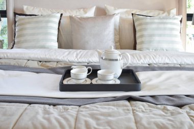 Çay seti modern yatak odasında yatağın üstüne siyah tepsisi ile dekoratif tepsi