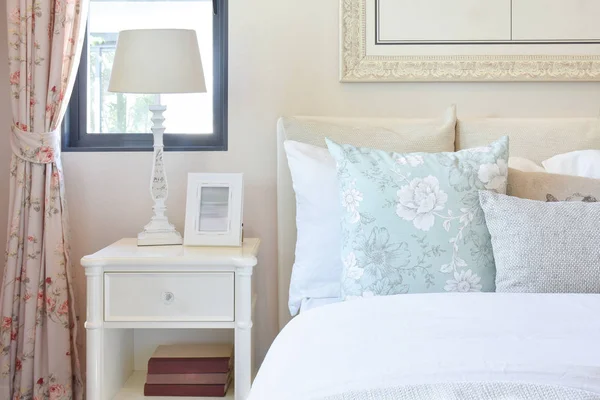 Винтажный интерьер спальни с лампой для чтения и рамкой на белом тумбочке — стоковое фото