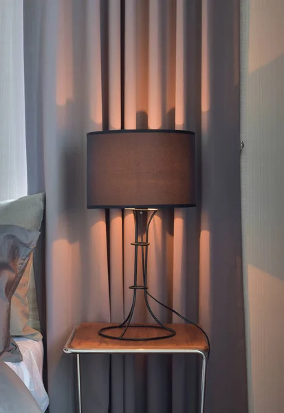 Black shade reading lamp next to bed