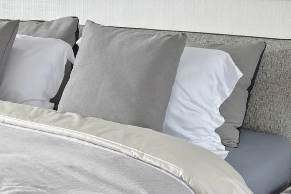 Ajuste de almohadas en la cama con ropa de cama de esquema de color gris —  Fotos de Stock