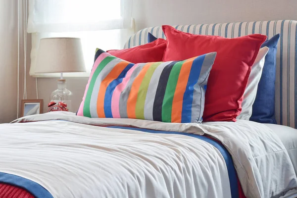 Striped headboard with colorful pillows and striped pillow on white bed sheet — Stock Photo, Image