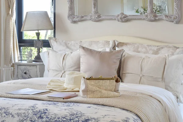 Interior del dormitorio de lujo con conjunto decorativo con bolso vintage, sombrero, libros sobre la cama y lámpara de mesa de estilo clásico — Foto de Stock