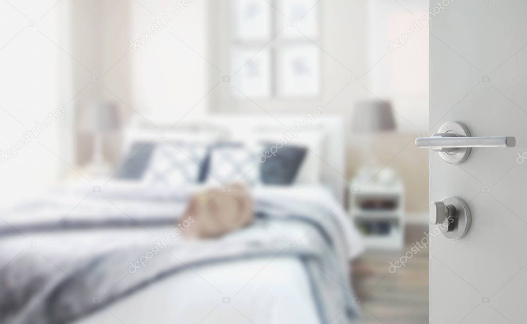 opened white door to blurred bedroom with bed