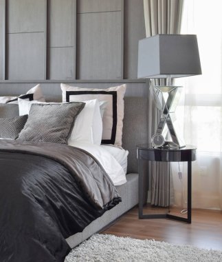 siyah desenli yastık yatak ve dekoratif masa lambası ile şık yatak odası iç tasarım.