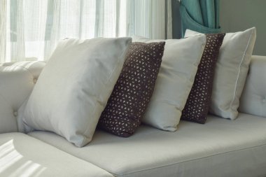 Satırı pencerenin yanındaki bej kanepe kahverengi ve beyaz yastıklar