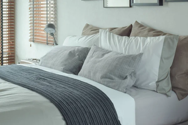 Dark gray bed runner with gray and brown pillows on bed