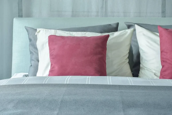 Red velvet pillows with white and gray pillows setting on bed in gray color scheme — Stock Photo, Image