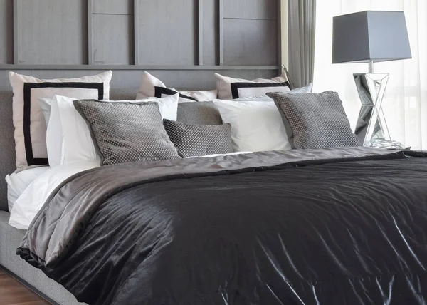 Стильный дизайн интерьера спальни с черными подушками с узором на кровати и декоративной настольной лампой . — стоковое фото