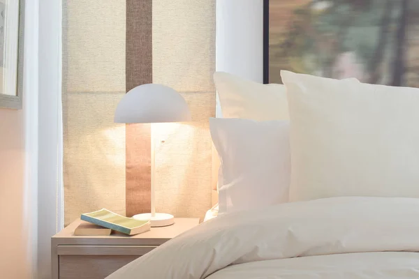 Cozy bedroom interior with pillows and reading lamp on bedside table