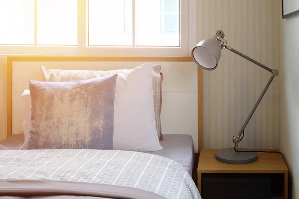베개와 침대 옆 테이블에 독서 용 램프와 아늑한 침실 인테리어 — 스톡 사진
