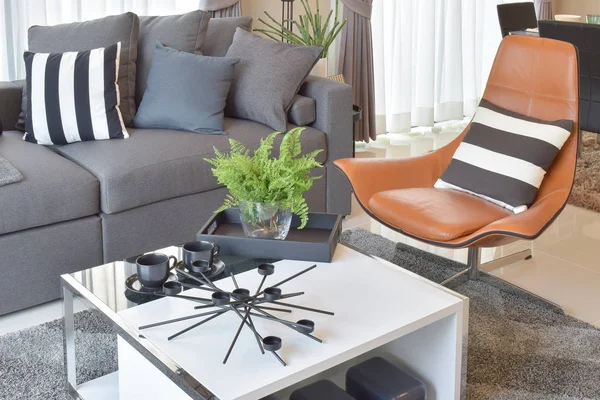 Elegante diseño de la sala de estar con almohadas grises en cómodo sofá y silla de cuero marrón — Foto de Stock