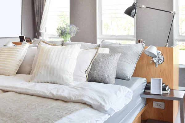 stylish bedroom interior design with white striped pillows on bed and decorative table lamp.