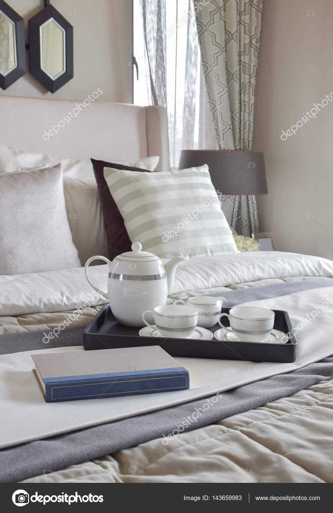 Decorative tray with book and tea set on the bed in modern bedroom