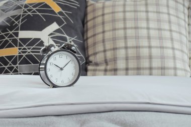 Klasik tarzı saat ve üzerinde beyaz keten yatak yastık