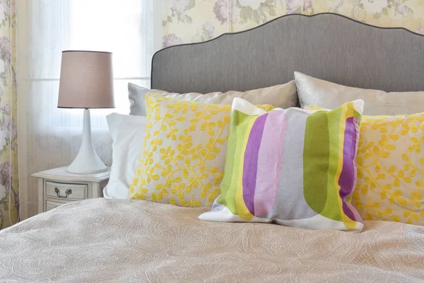 Dormitorio femenino con almohadas de colores en la cama en el dormitorio de estilo vintage . — Foto de Stock