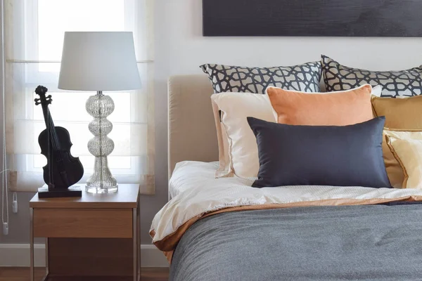 Сучасний інтер'єр спальні з помаранчевими і золотими подушками на ліжку і настільній лампі — стокове фото