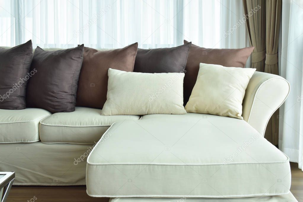 L shape beige sofa with varies brown color of pillows