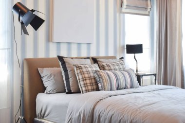 çizgili yastık yatak ve dekoratif lamba ile şık yatak odası iç tasarım.