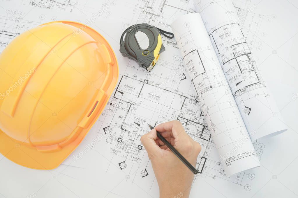 Architect working on construction blueprint. Architects workplace - architectural project, blueprints, helmet, measuring tape, Construction concept. Engineering tools. Top view