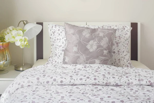 Pequeña ropa de cama de estilo lavanda en el dormitorio con orquídea blanca al lado de la cama . —  Fotos de Stock