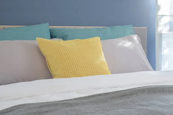 与设置在现代室内卧室的床上的黄色，浅的灰色和绿色枕头 — 图库照片