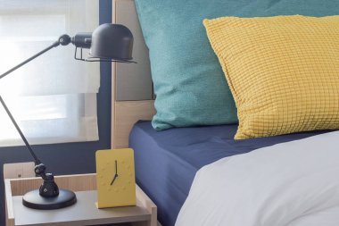 Sarı modern saat başucundaki ile arka planda renkli yastıklar
