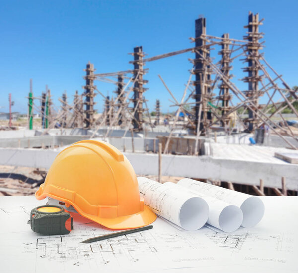 архитектурный чертеж с защитным шлемом и инструментами на строительной площадке для жилищного строительства
