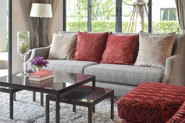 Moderno diseño de la sala de estar con almohadas rojas en el sofá y lámpara de mesa decorativa — Foto de Stock
