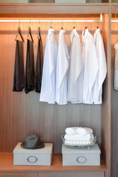 Řada bílé košile a černé kalhoty, v dřevěné skříni — Stock fotografie