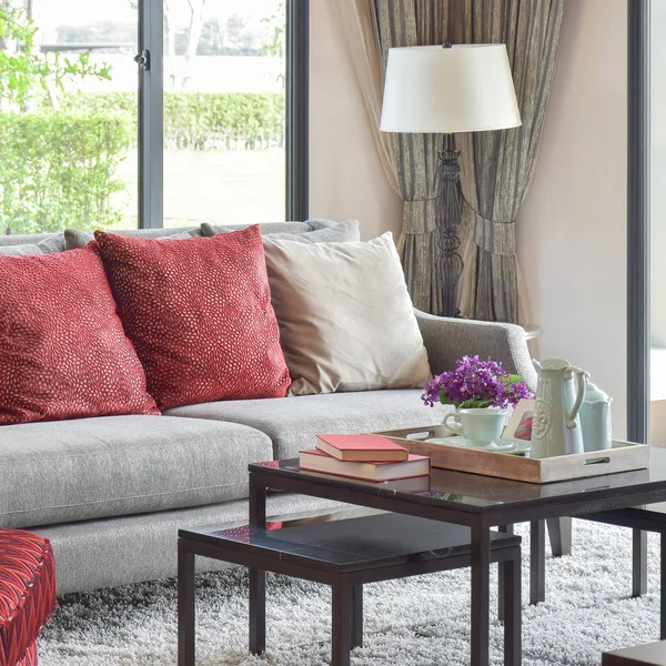 Moderne dagligstuedesign med røde puter på sofa og dekorativt teservise på bordet – stockfoto