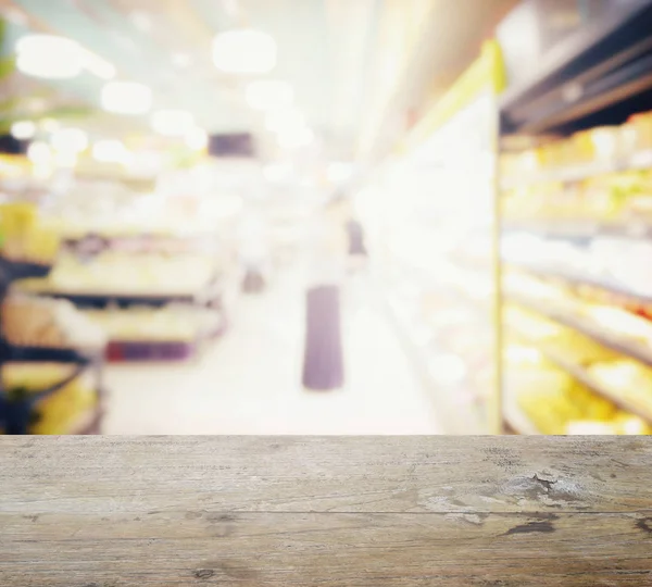 Holztischplatte mit Verwischung des Supermarktes mit verschiedenen Produkten in den Regalen — Stockfoto