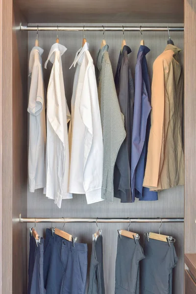 Classic color shirts are hanging in open wooden wardrobe — Stock Photo, Image