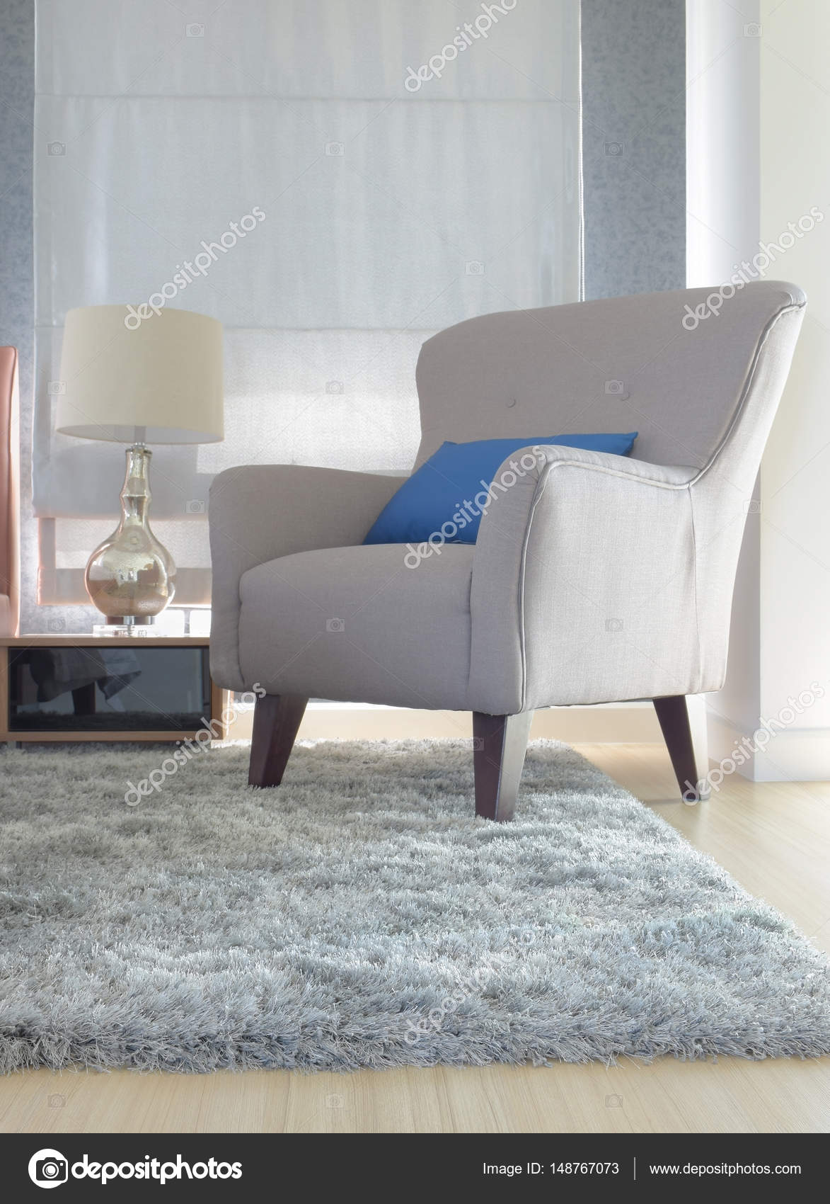 Grijze bekleding fauteuil met blauw kussen in moderne interieur ... Grijze bekleding fauteuil met blauw kussen in moderne interieur ...