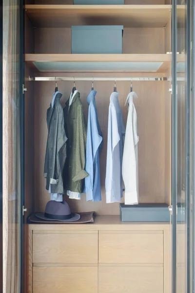 Modern style wooden closet with shirts hanging on rail — Stock Photo, Image