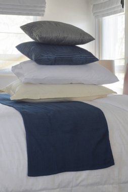 Duvar ve pencere arka planda yatak üzerinde yığın yastıklar