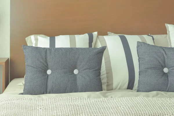Gray and brown strip pillows setting on bed with brown headboard — Stock Photo, Image