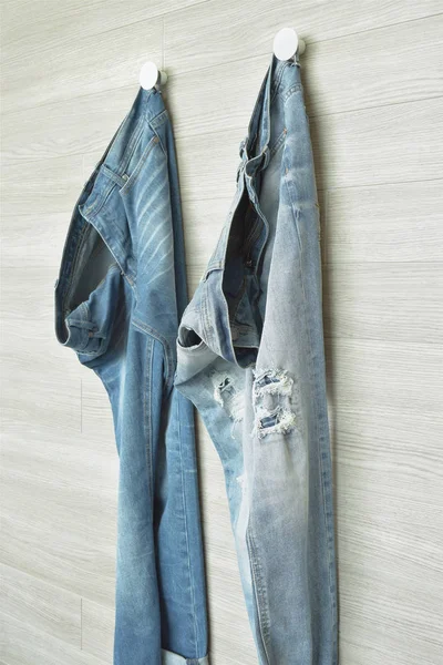Jeans hanging on wooden wall walk in closet — Stock Photo, Image