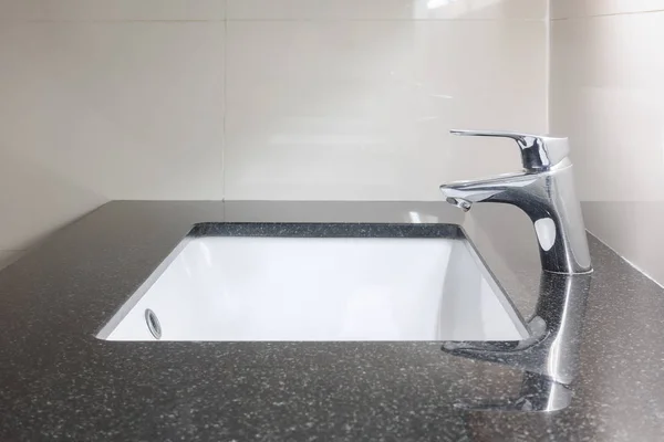 Under counter toalett med svart granit topp och kran — Stockfoto