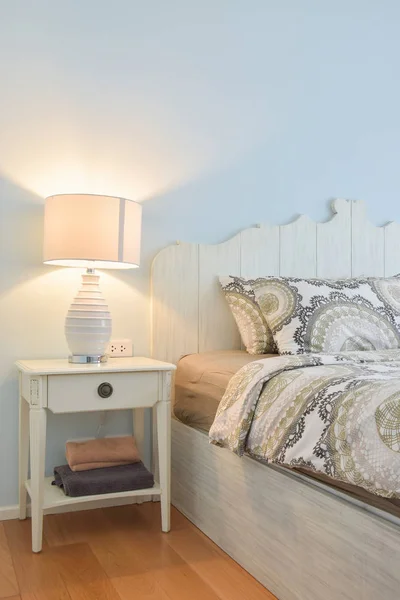 White reading lamp next to modern country style bedding