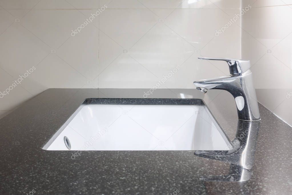 Under counter lavatory with black granite top and faucet