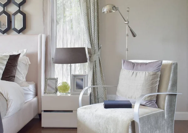 Modern bedroom interior with gray pillow on armchair and bedside table lamp at home — Stock Photo, Image