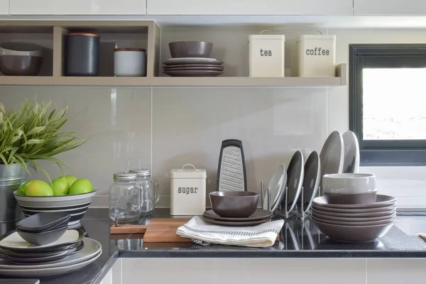 Keramikgeschirr und -schalen auf der Theke und im Regal in der modernen Küche — Stockfoto