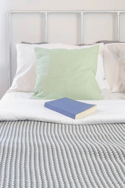 Buch auf dem Bett mit Pastellkissen-Set und Streifendecke — Stockfoto