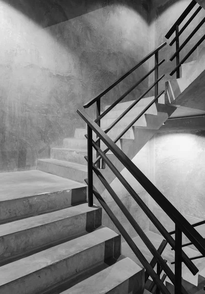 Empty modern rough concrete stairway with black steel handrail